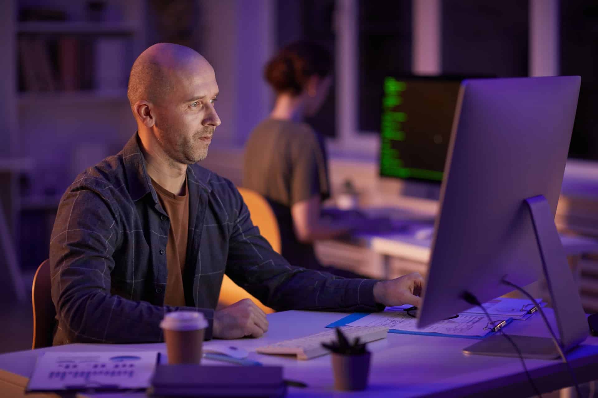 man works on computer with purple lighting