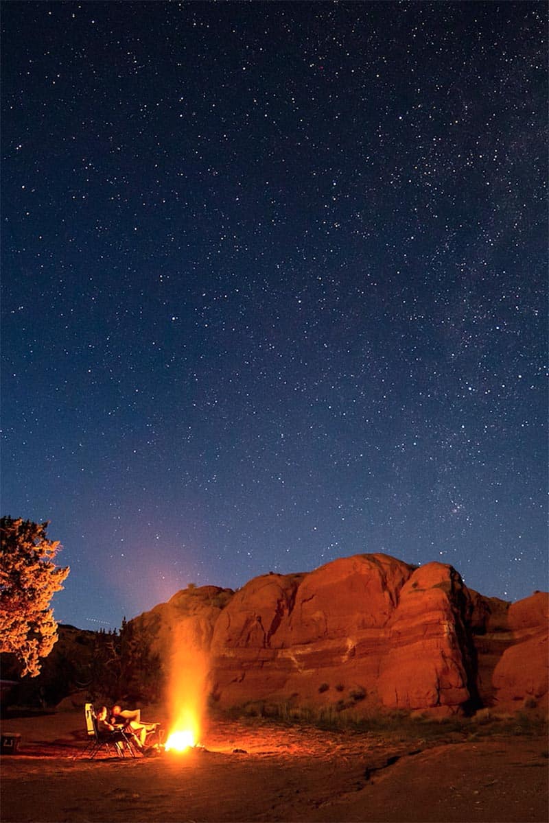 fire pit at night in front of red rock with starry sky in Utah