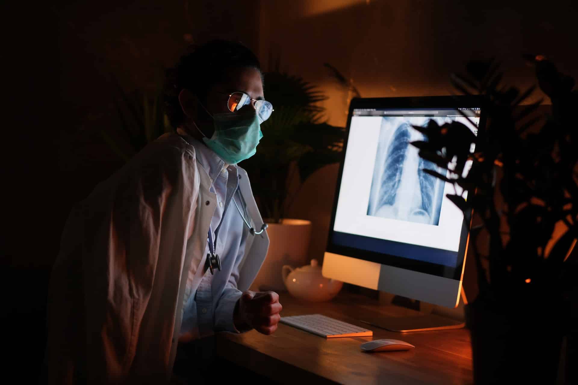 nurse with mask examines x-ray - IT services for healthcare