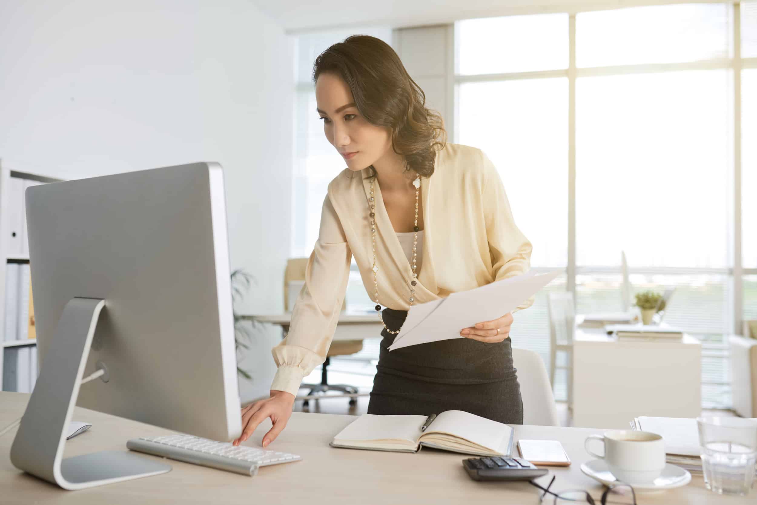 Woman standing up working at desktop computer