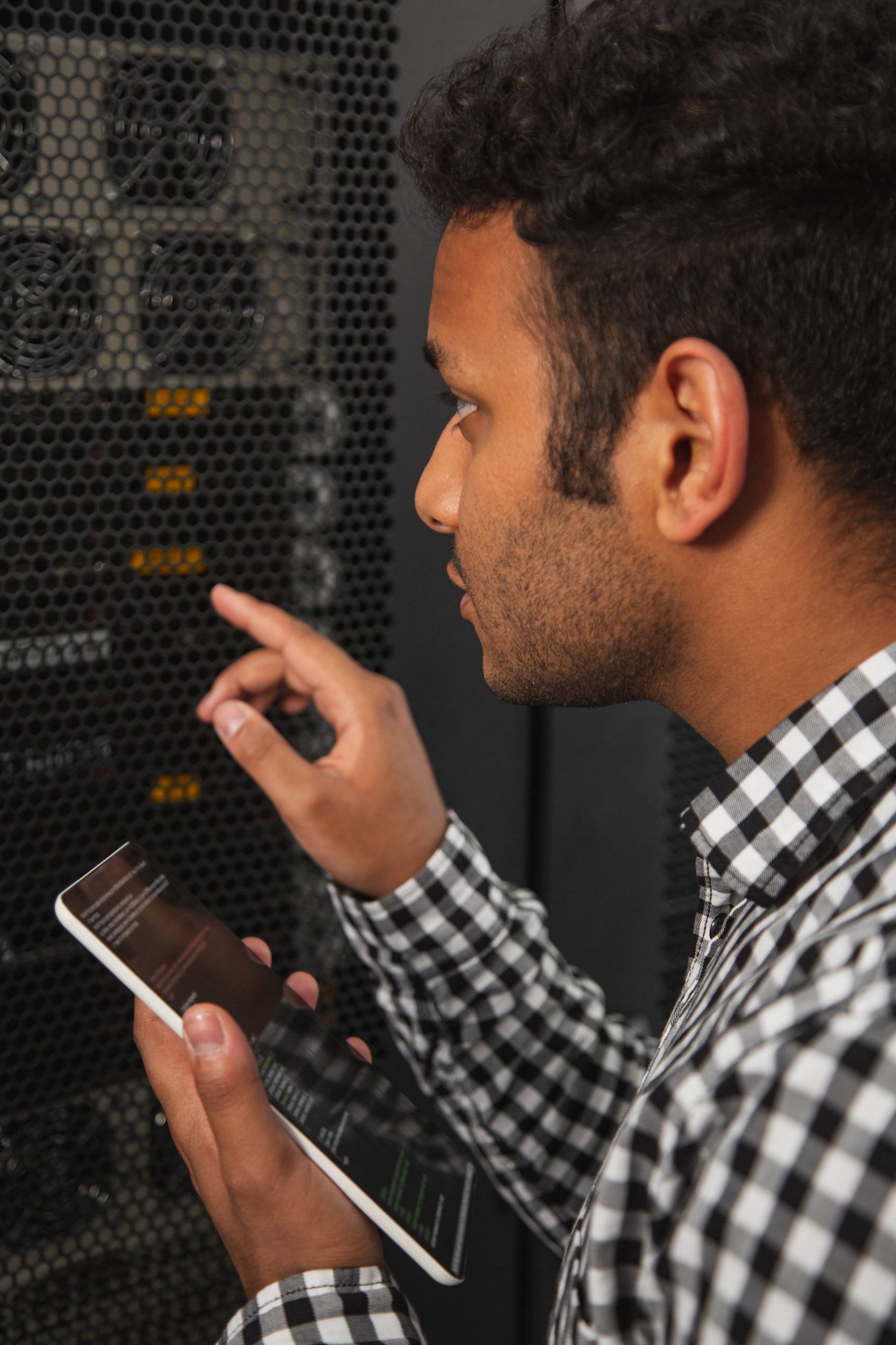 Man looking at server rack while holding cellphone