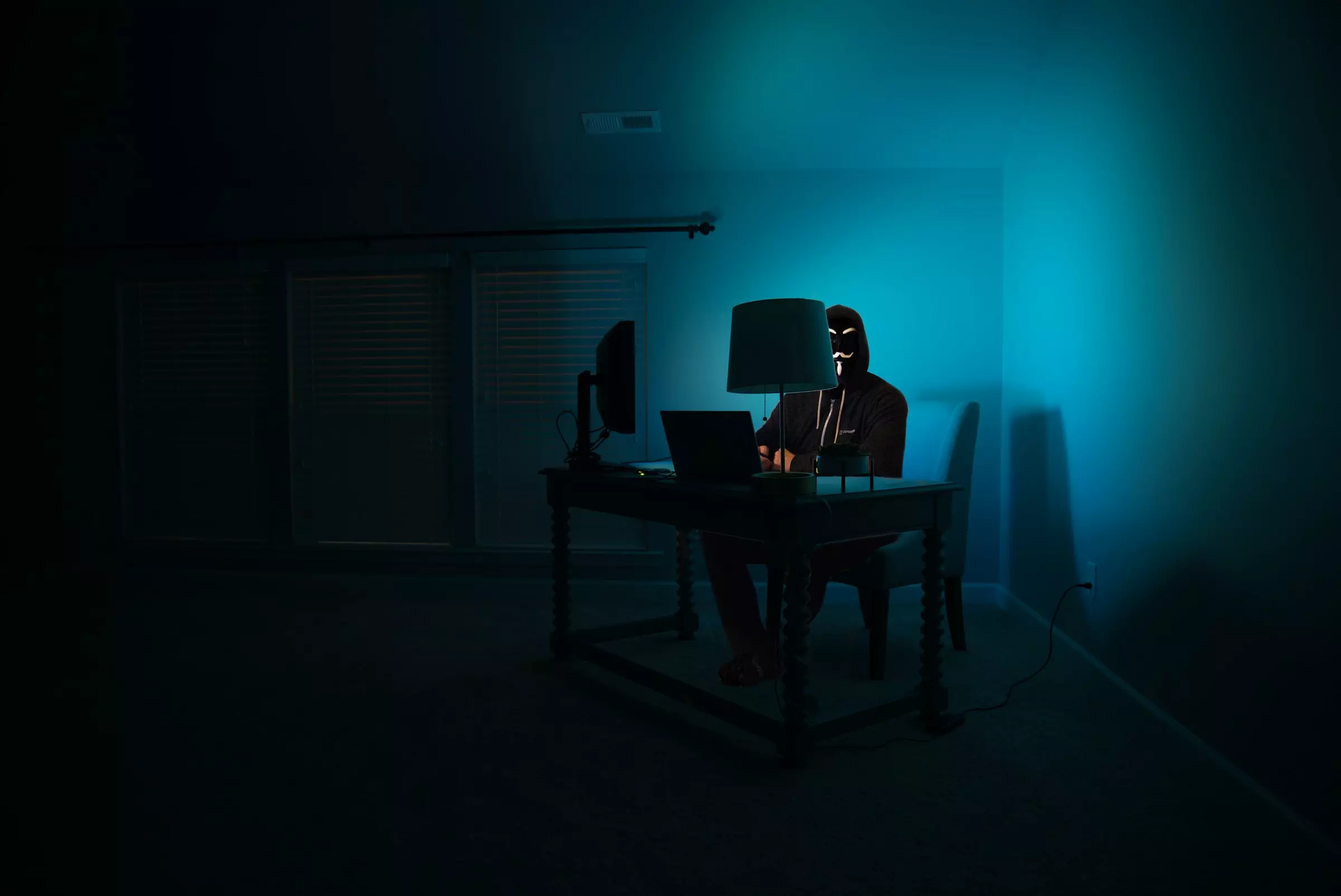 Hacker in dark corner of room with monitor screen lighting his face