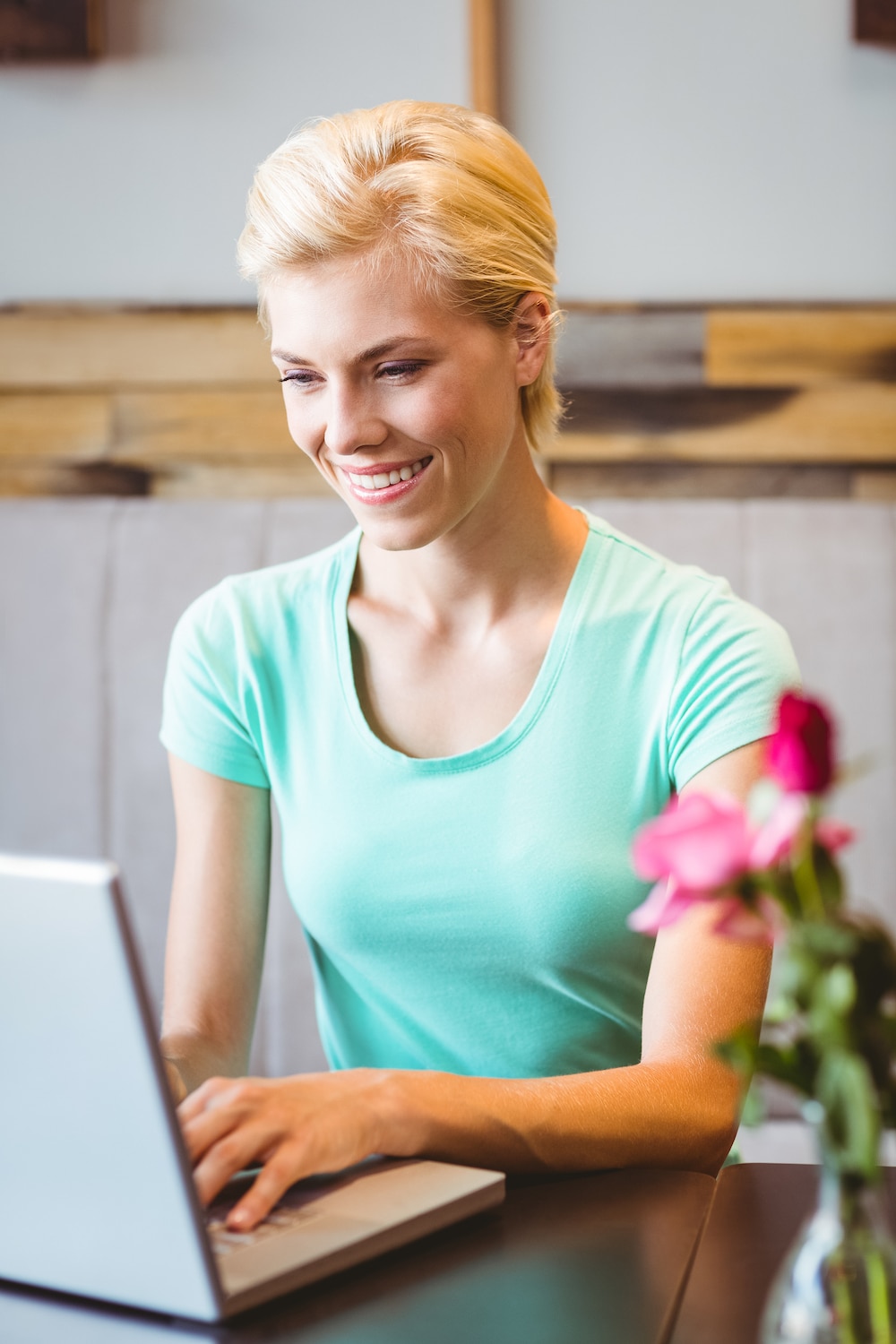 Blonde haired woman working on laptop in green shirt