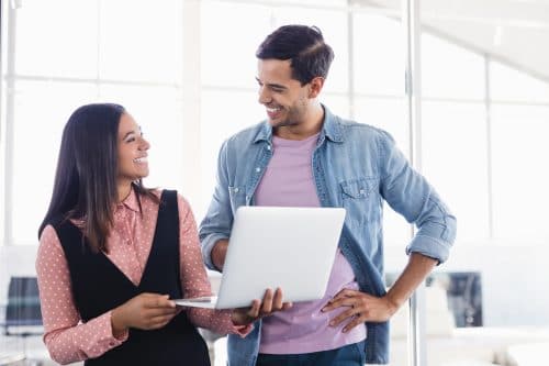 Man and woman using laptop and smiling