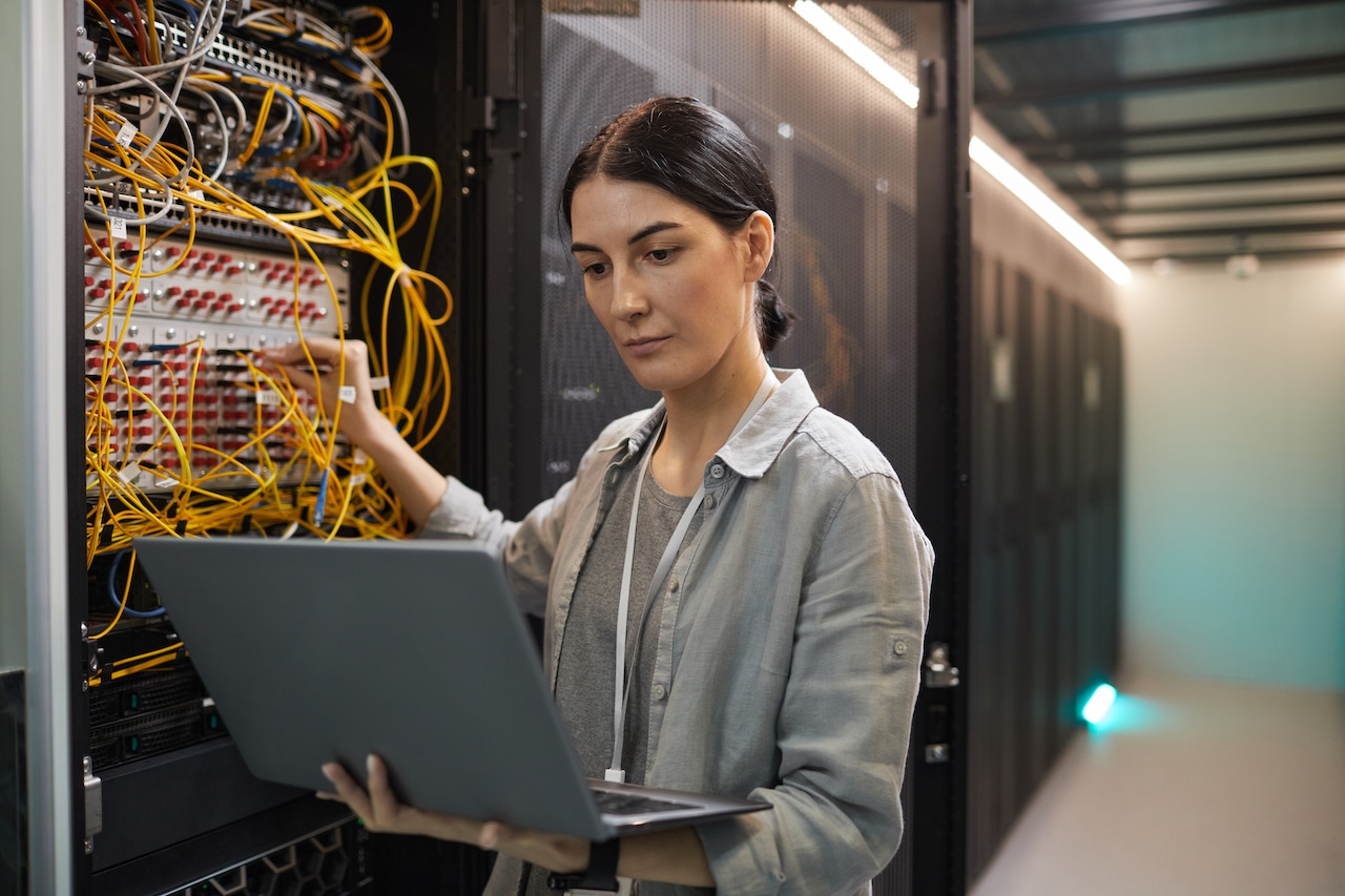 female network technician in server room ensuring proper remote workplace cybersecurity
