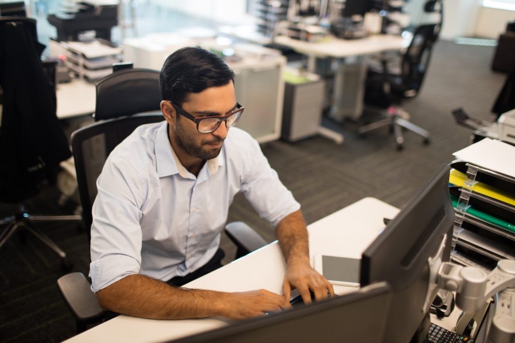 man in office using outsourced it solutions to stay optimized with tech