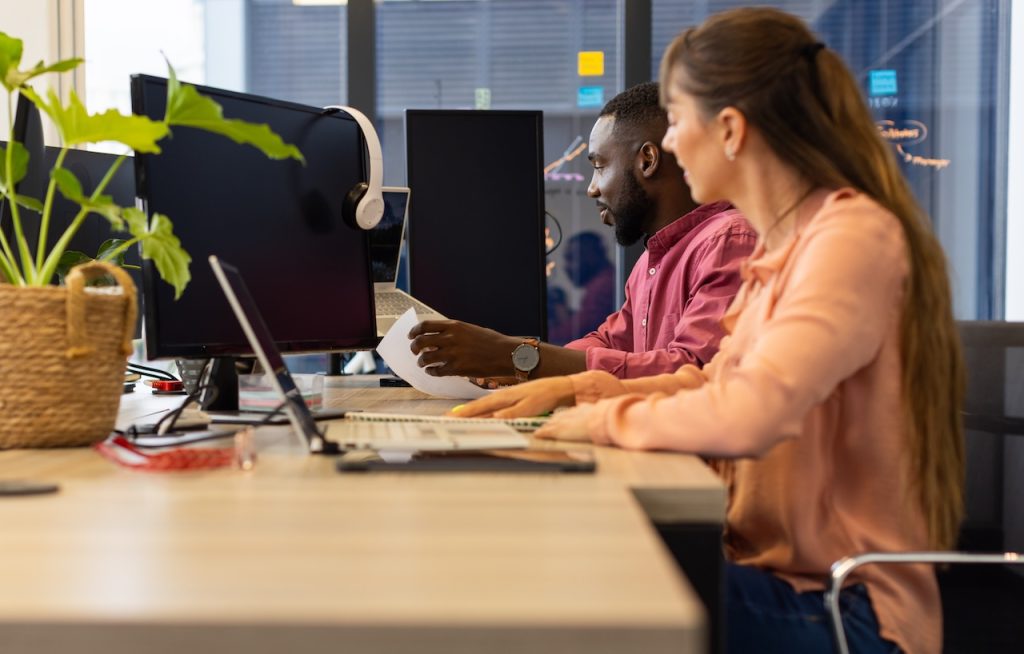 male and female coworkers working at desk in office with business it support