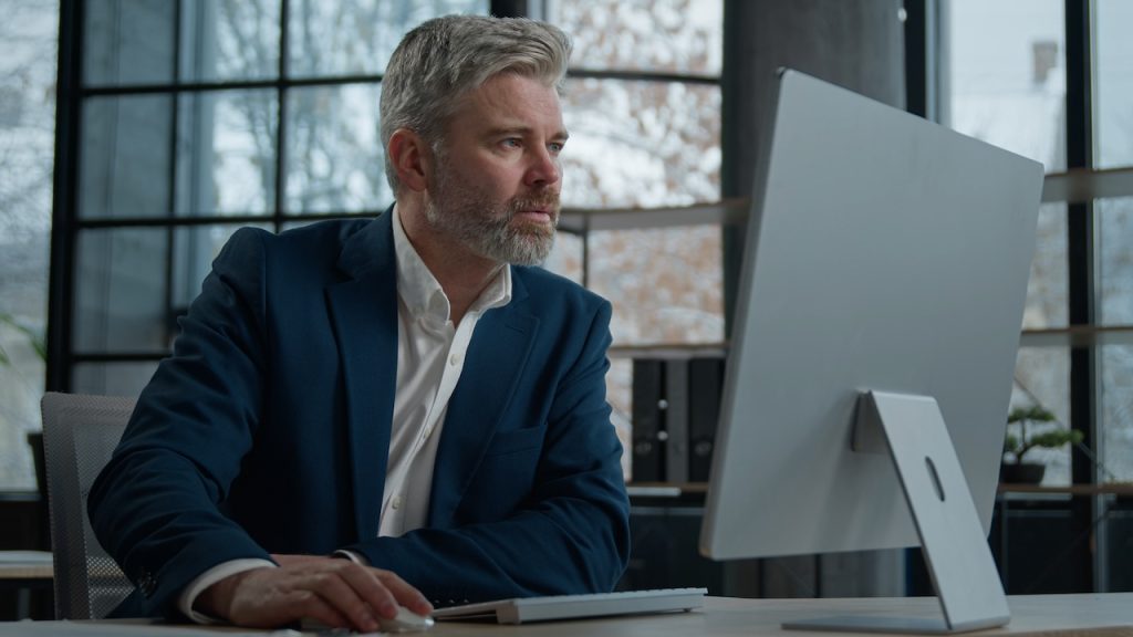 male employee at work reviewing computer after IT security risk assessment