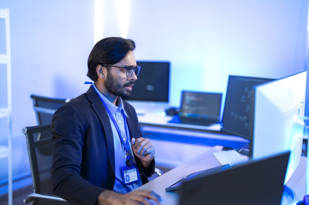 man working on computer in office with blue lighting