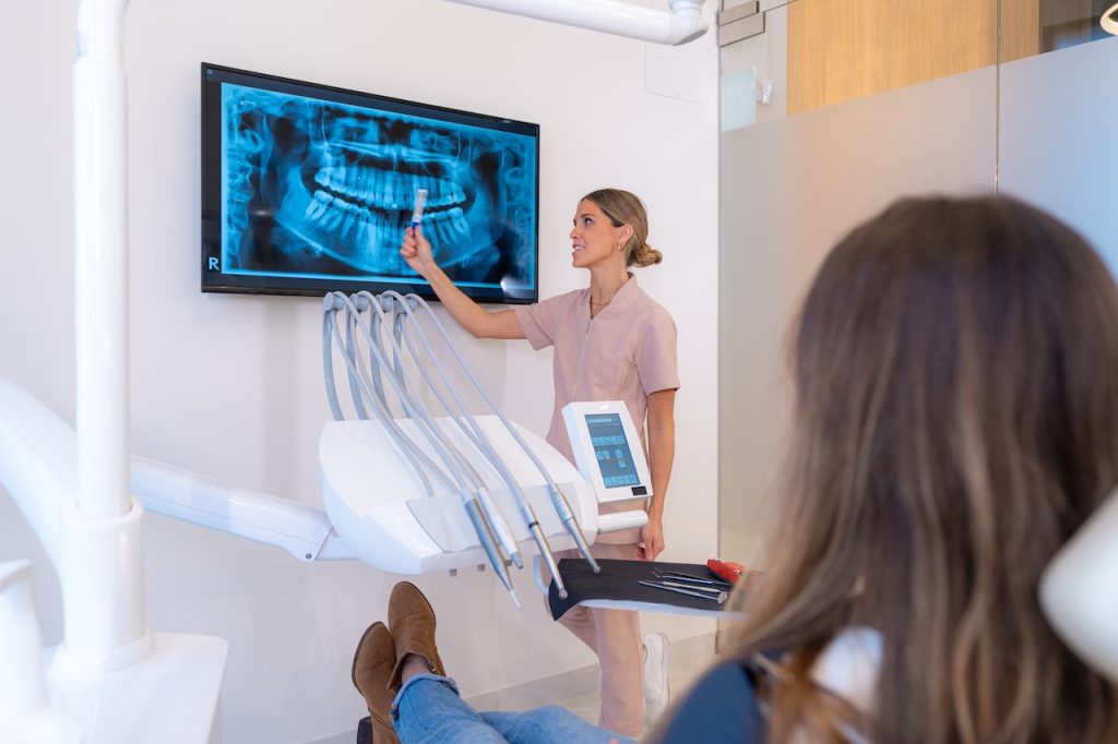 Dentist showing X ray image to patient sitting on a chair