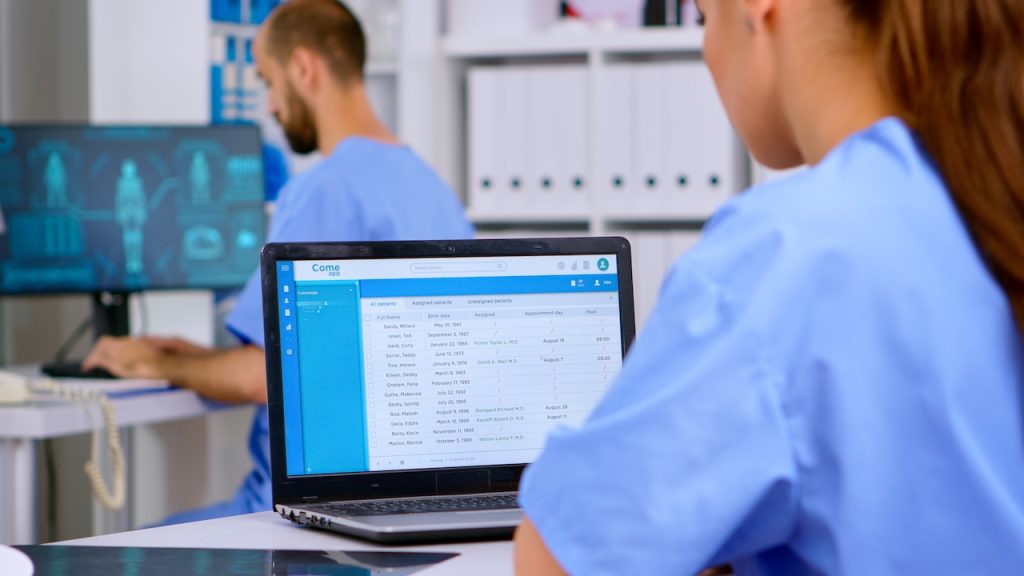 medical professional reviewing records with help from medical office IT support