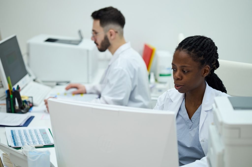 Medical professionals working in a lab environment, analyzing data on computer