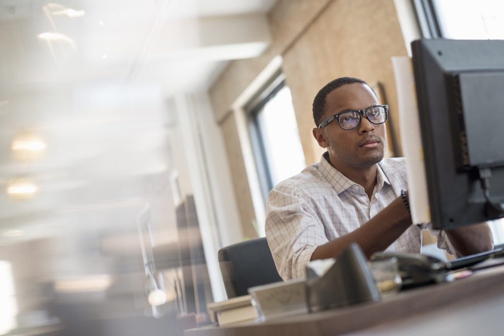A man seated at a desk using a computer