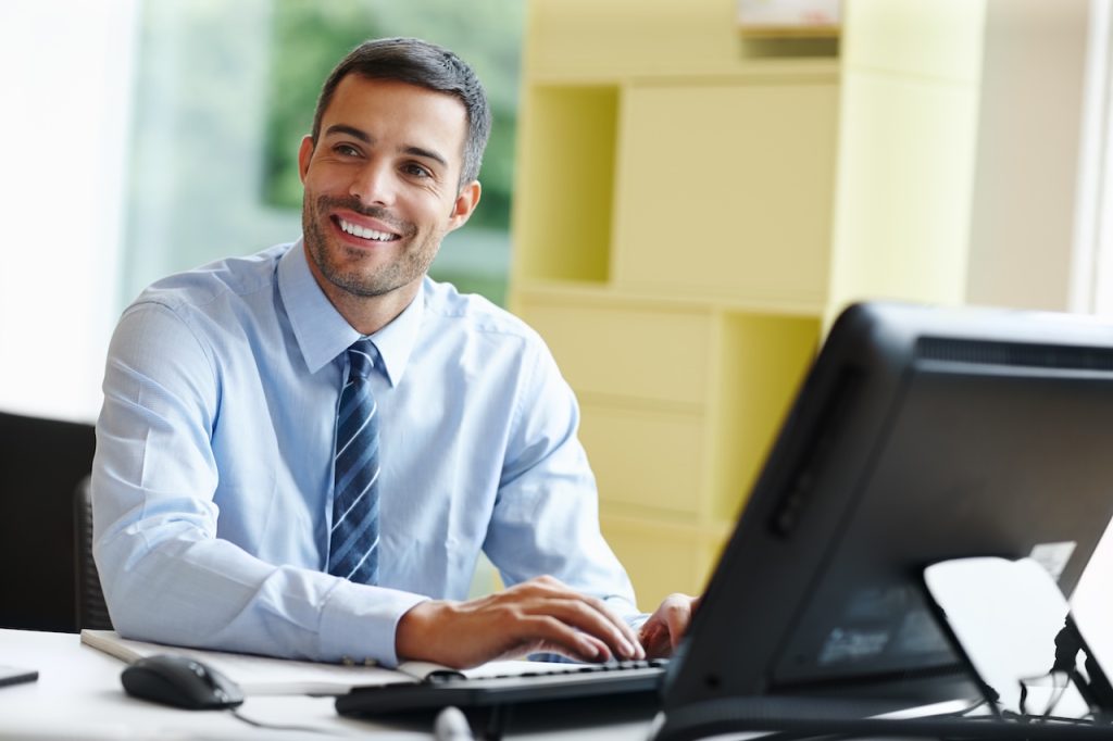 businessman working on computer in office, smiling off to the side