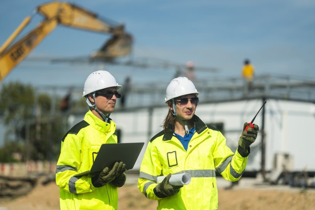 construction workers on site using computer and radio