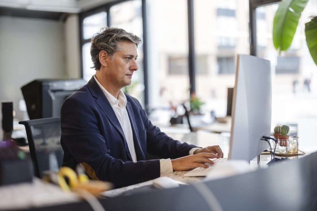 Mature businessman concentrating on his work while typing on a computer keyboard in office
