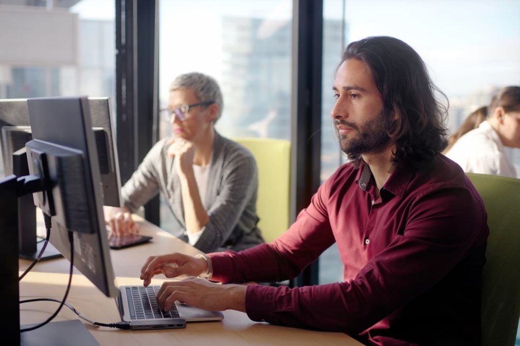 man working on computer in office with coworkers