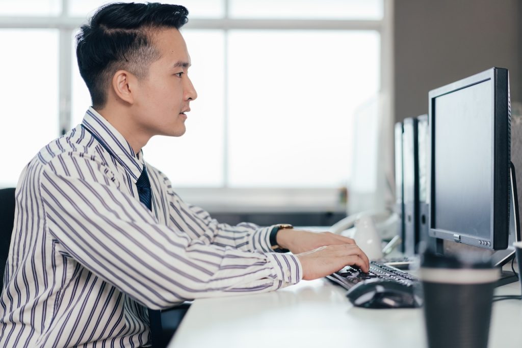 man typing on computer at work